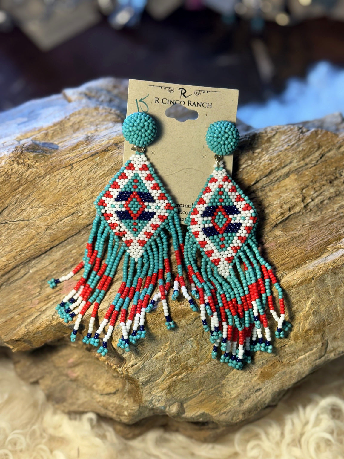 Turquoise seed bead fringe earrings with red, white, navy, and green geometric beadwork
