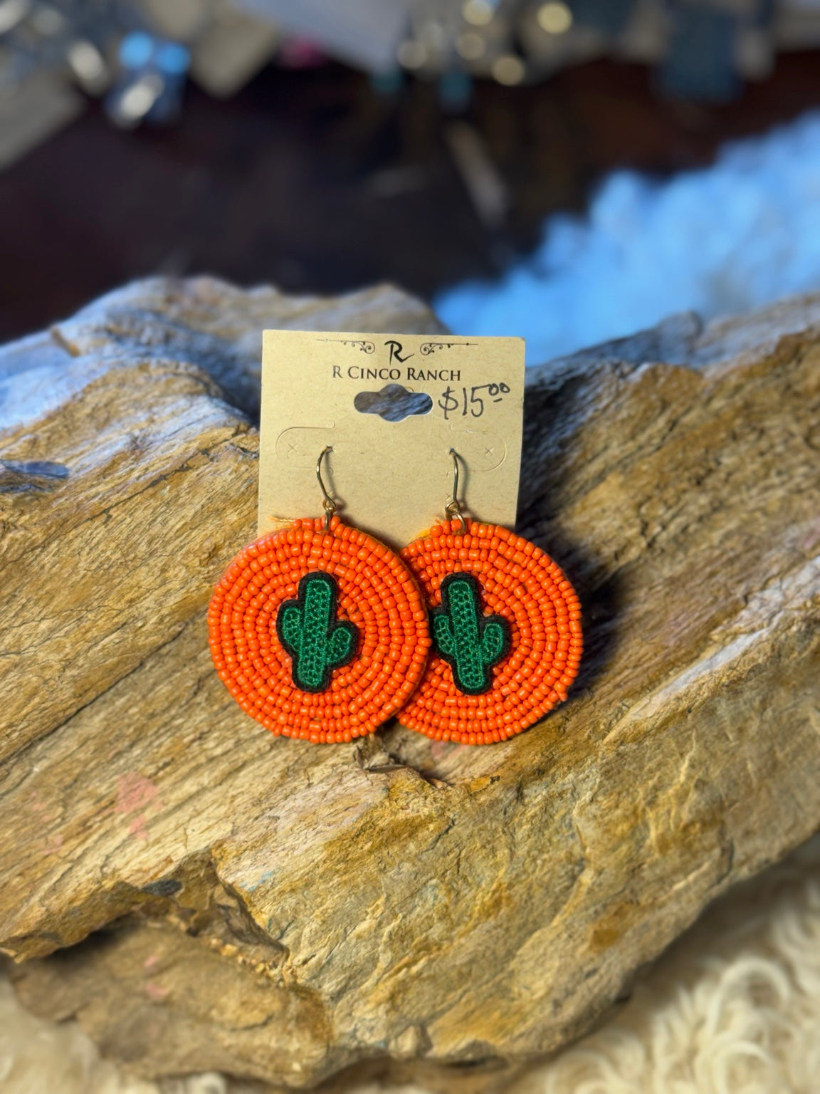 Bright orange circular seed bead earrings with green cactus motifs
