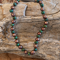 African turquoise necklace with green stone beads and bronze-colored accent beads on rustic wood
