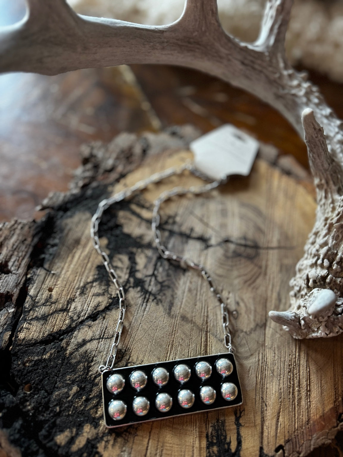 Black rectangular statement necklace with raised silver-tone bubble accents