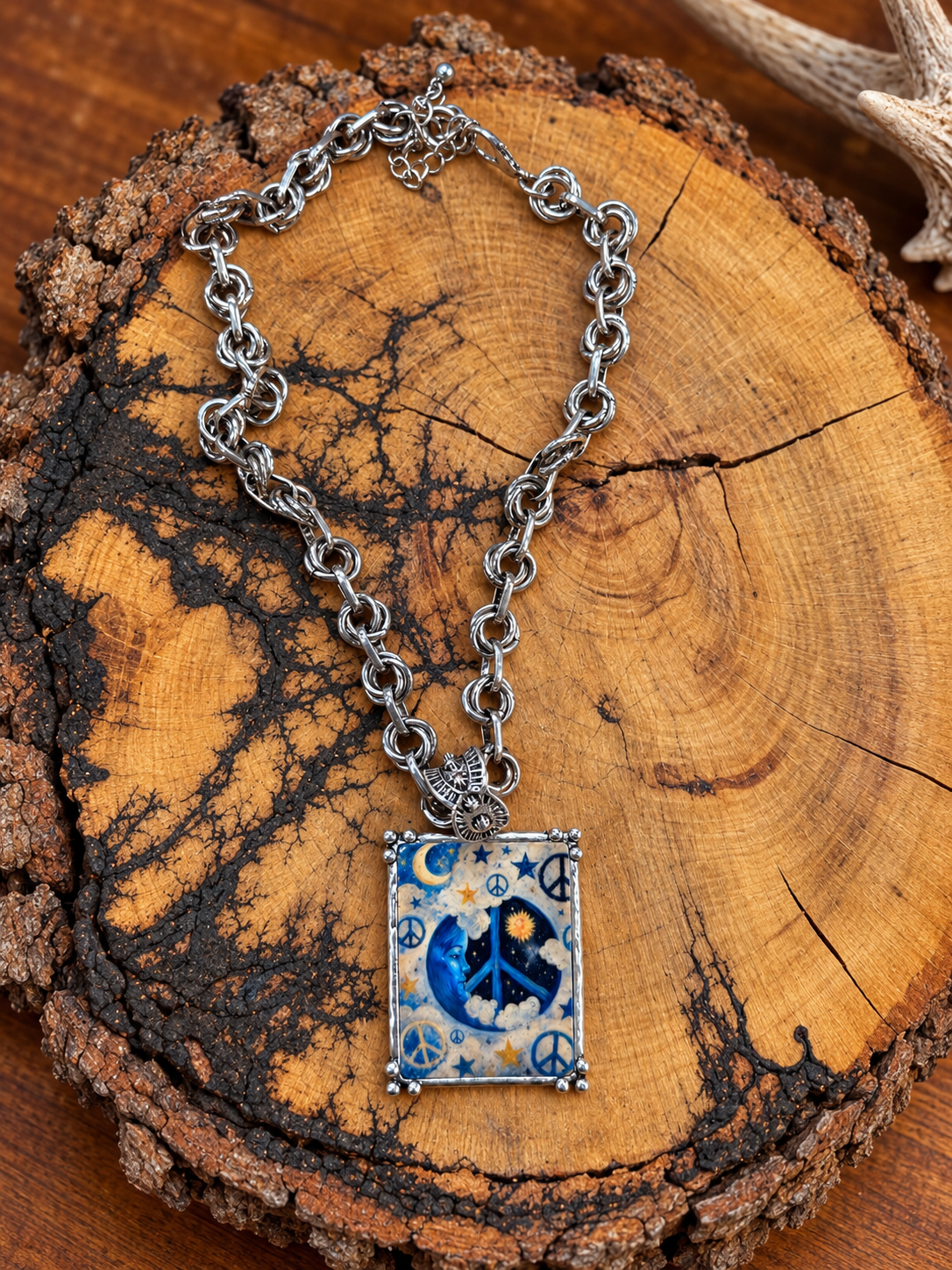 Blue moon and peace sign rectangular pendant necklace with silver-tone double-ring chain on rustic wood