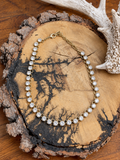 Clear round crystal link necklace with gold-tone links and extender on a rustic wood slice
