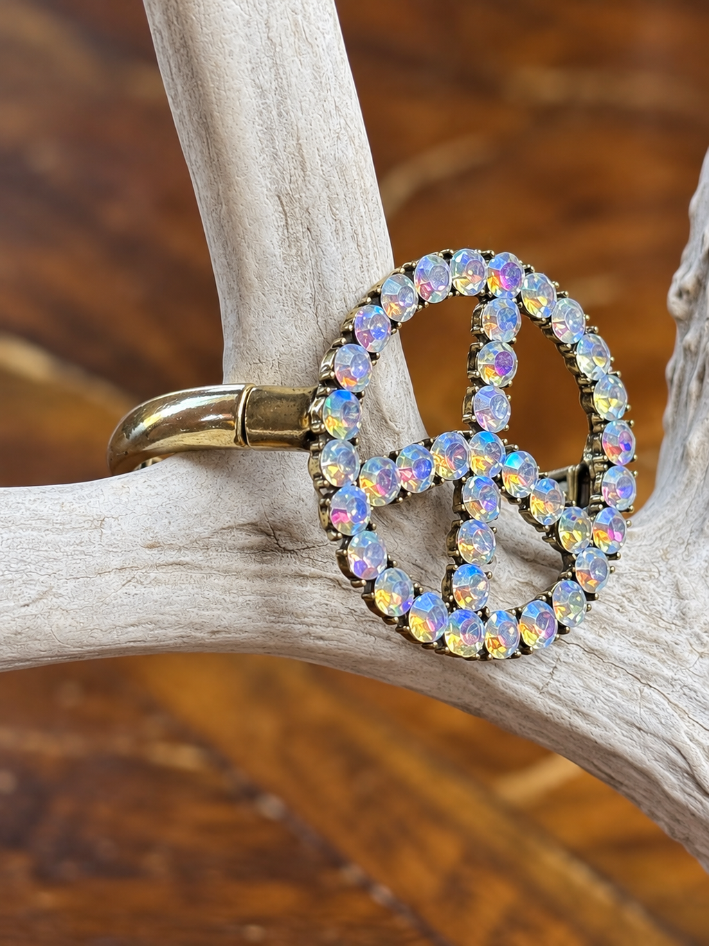 Side view of clear rhinestone peace sign bracelet showing gold-tone band
