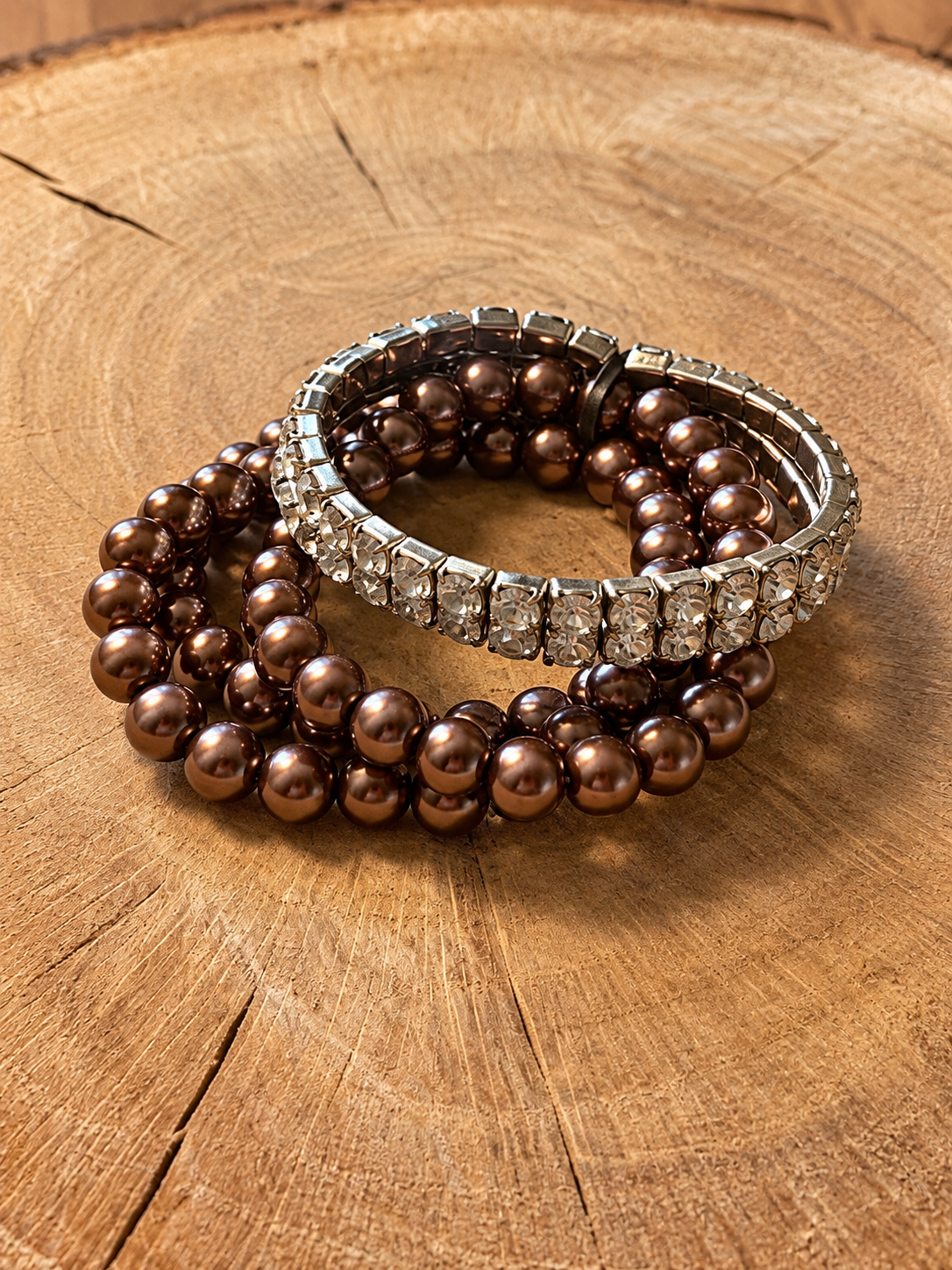 Copper-tone five-piece beaded and rhinestone bracelet set on natural wood