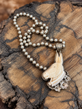 Dash the Donkey carved bone pendant with silver-tone flowers and 6 mm faux Navajo pearl beads on rustic wood