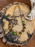Iridescent round crystal necklace with adjustable chain on a rustic wood slice