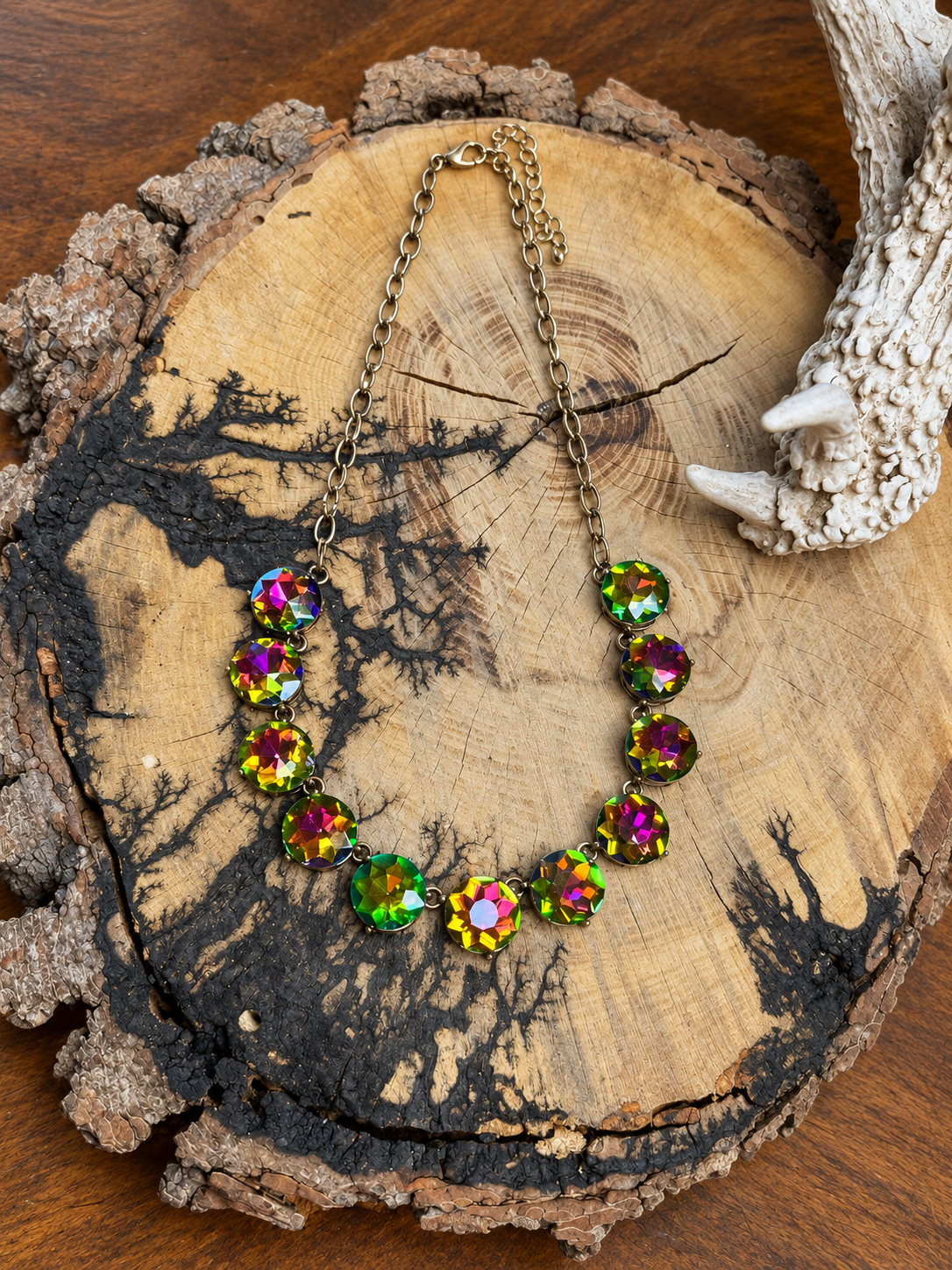 Iridescent round crystal necklace with adjustable chain on a rustic wood slice