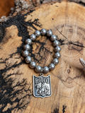 Silver-tone beaded bracelet with a Rodeo shield charm featuring a bronc rider and star on a rustic wood slice