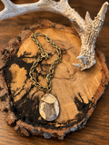Genuine jasper teardrop pendant with natural cream, tan and brown pattern on an antiqued gold-tone chain, displayed on rustic wood