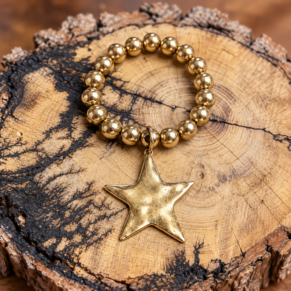 Gold-tone round bead bracelet with a large star charm on a rustic wood display