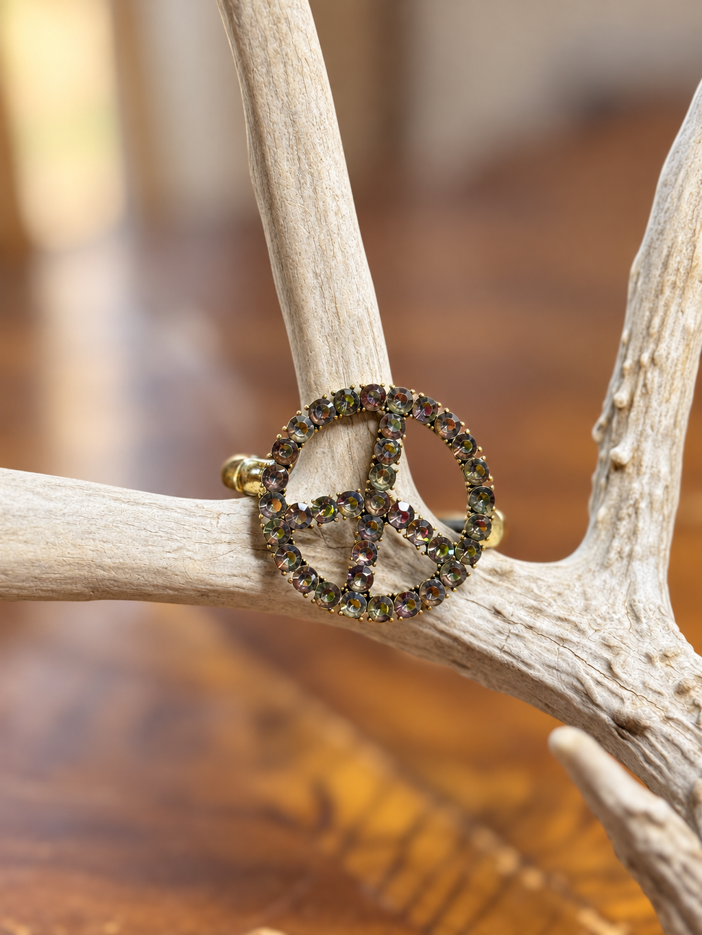 Iridescent rhinestone peace sign bracelet with gold-tone band, front view