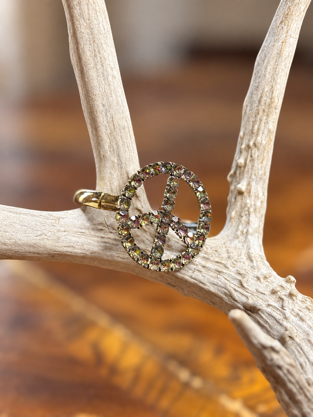 Iridescent rhinestone peace sign bracelet with gold-tone band, side view