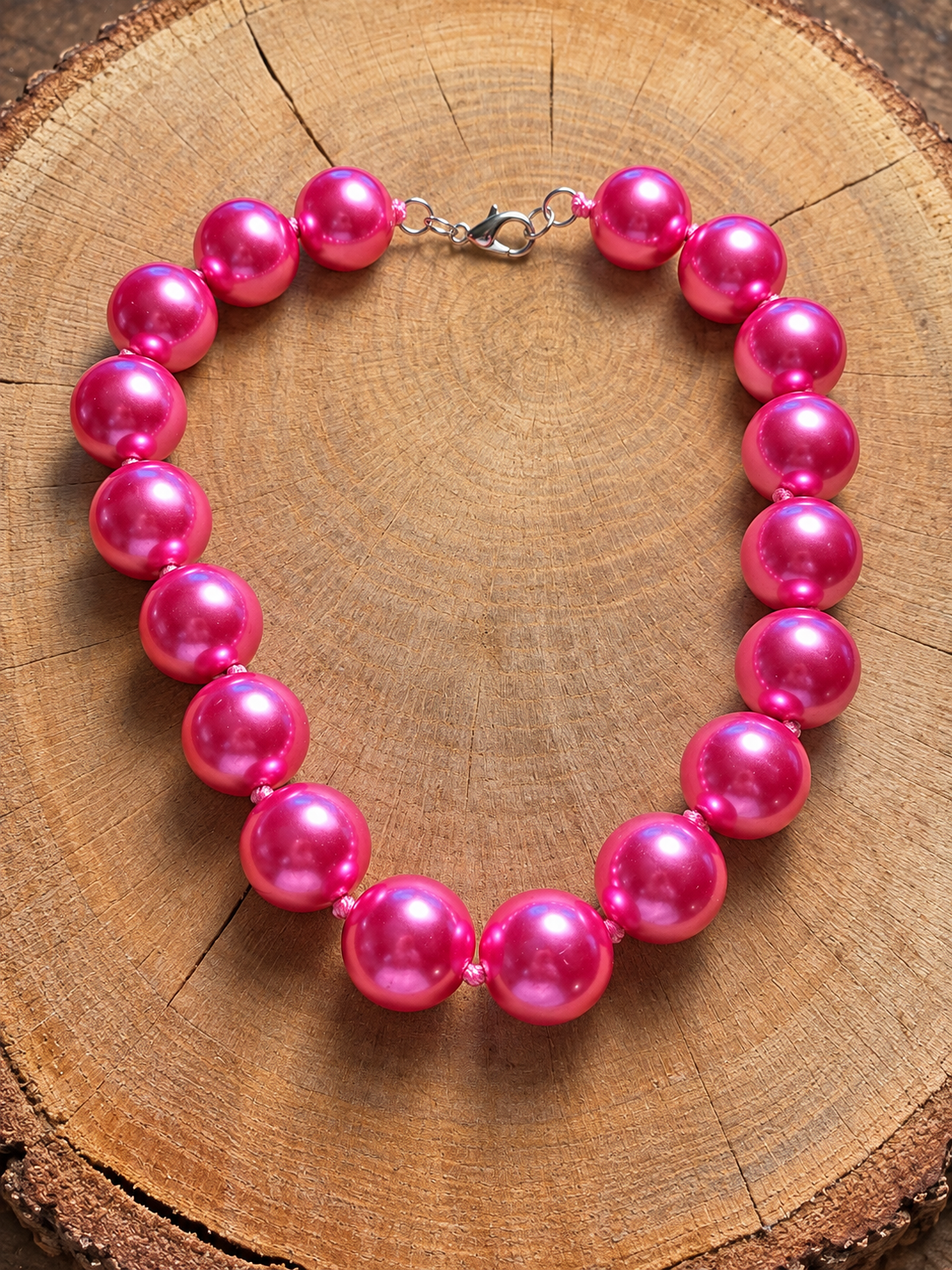 Hot pink pearl-finish beaded necklace on natural wood