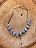 Iridescent round rhinestone statement necklace with antiqued chain on wood