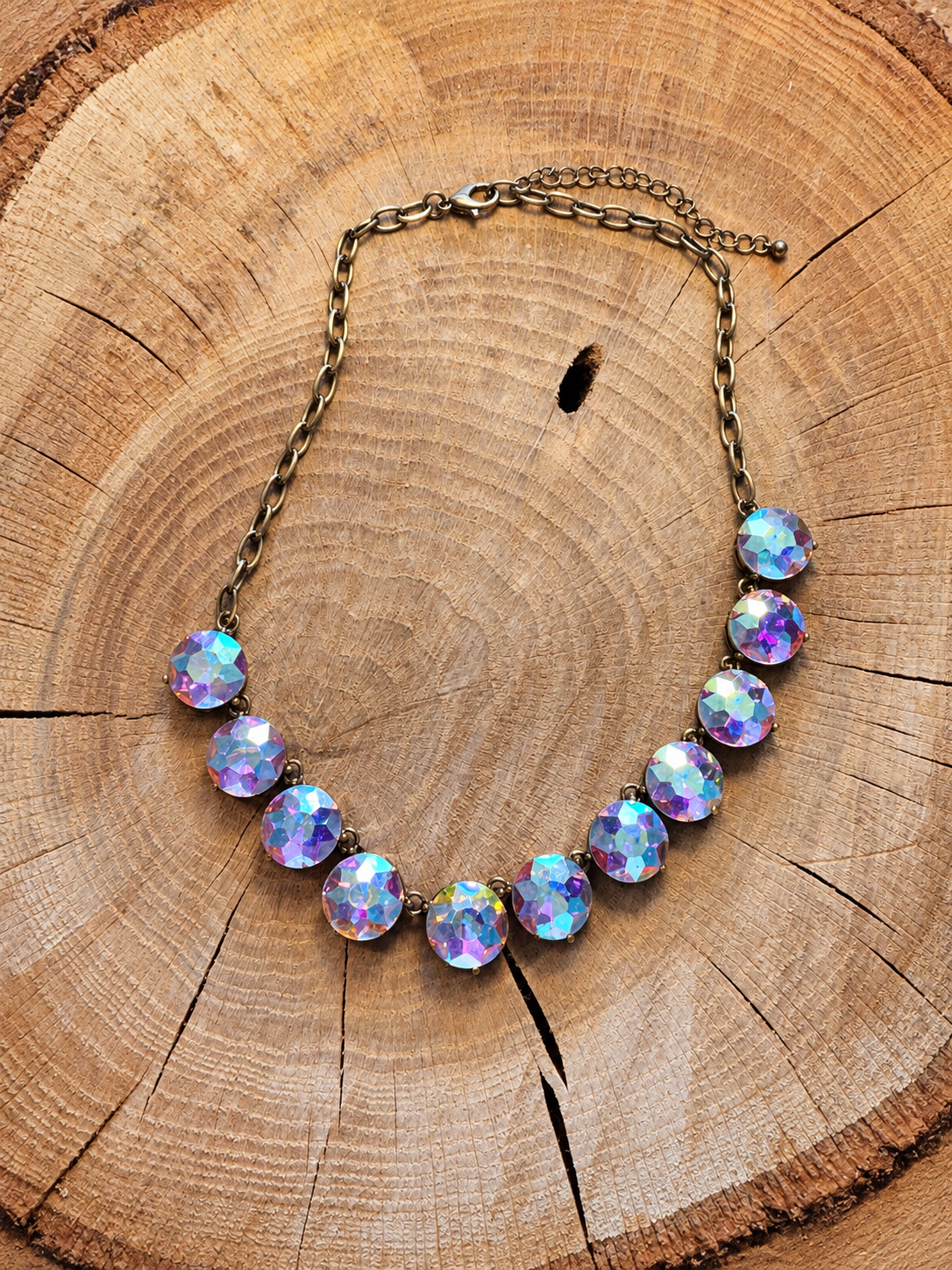 Iridescent round rhinestone statement necklace with antiqued chain on wood