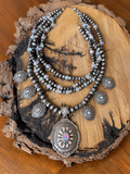 Layered silver-tone necklace with iridescent crystals, six small concho charms and an oval floral pendant.