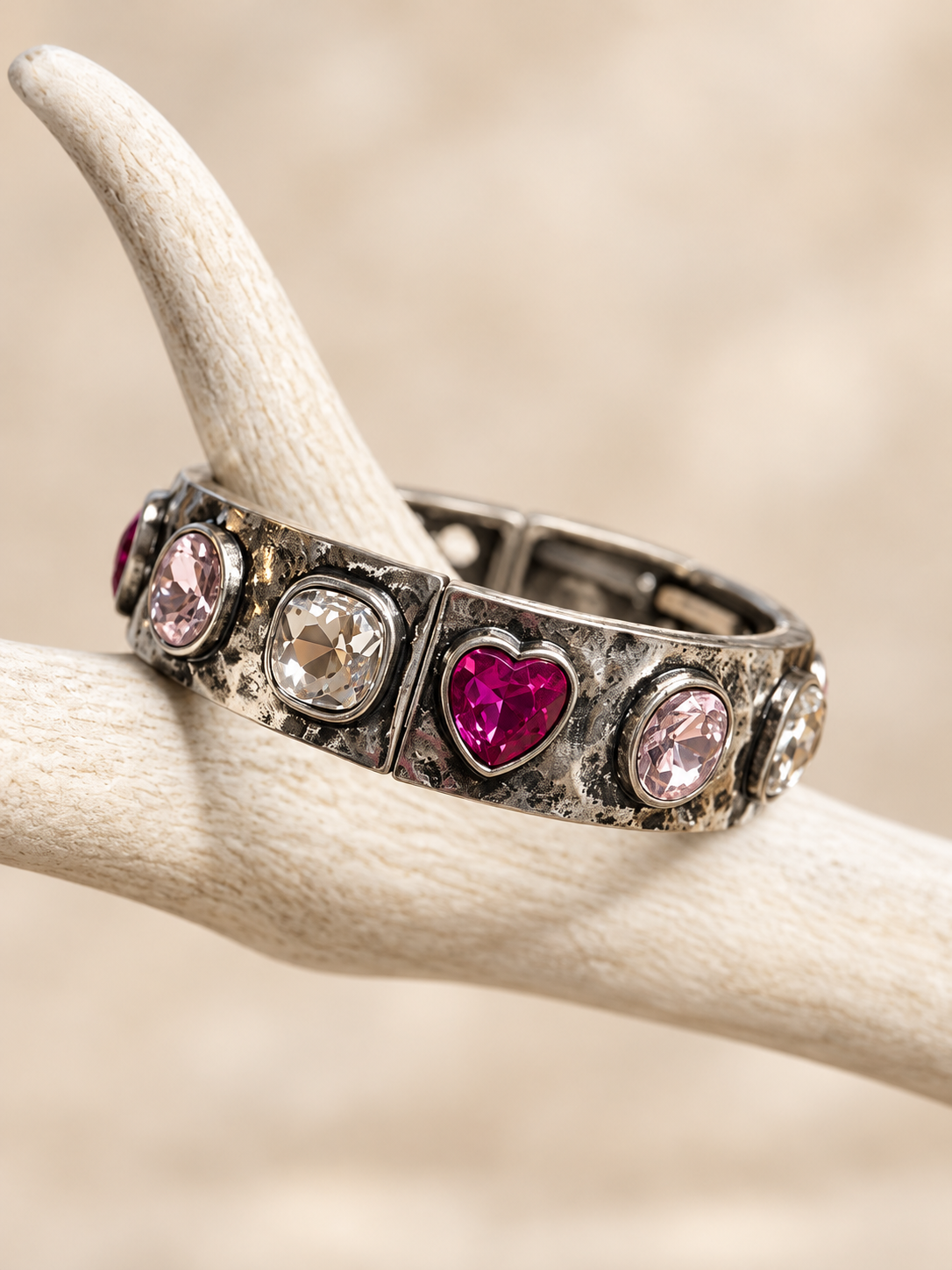 Antiqued silver-tone bracelet with a fuchsia heart, blush pink and clear crystals on an antler display