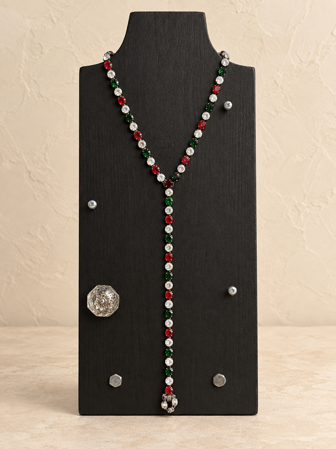 Red, green and clear crystal magnetic Y necklace styled with a long drop on a black stand