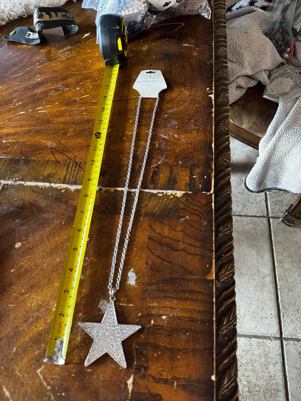 Long silver-tone rhinestone star pendant necklace shown beside measuring tape