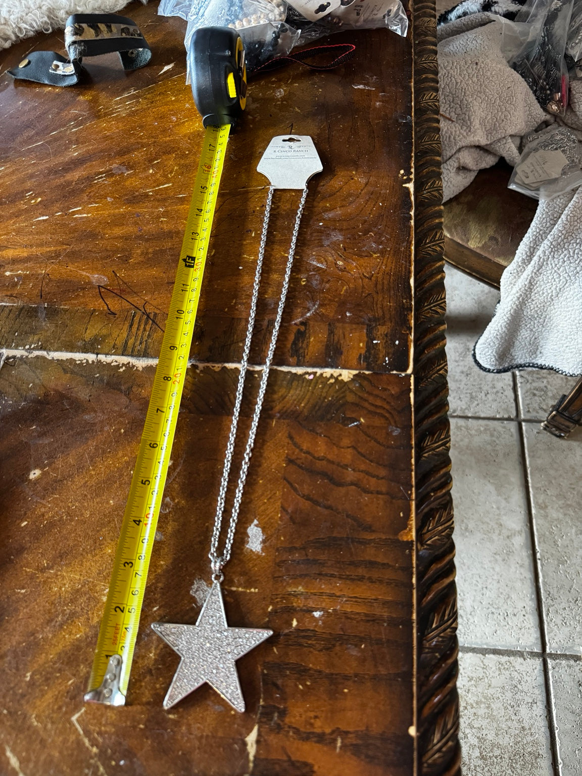 Long silver-tone rhinestone star pendant necklace shown beside measuring tape