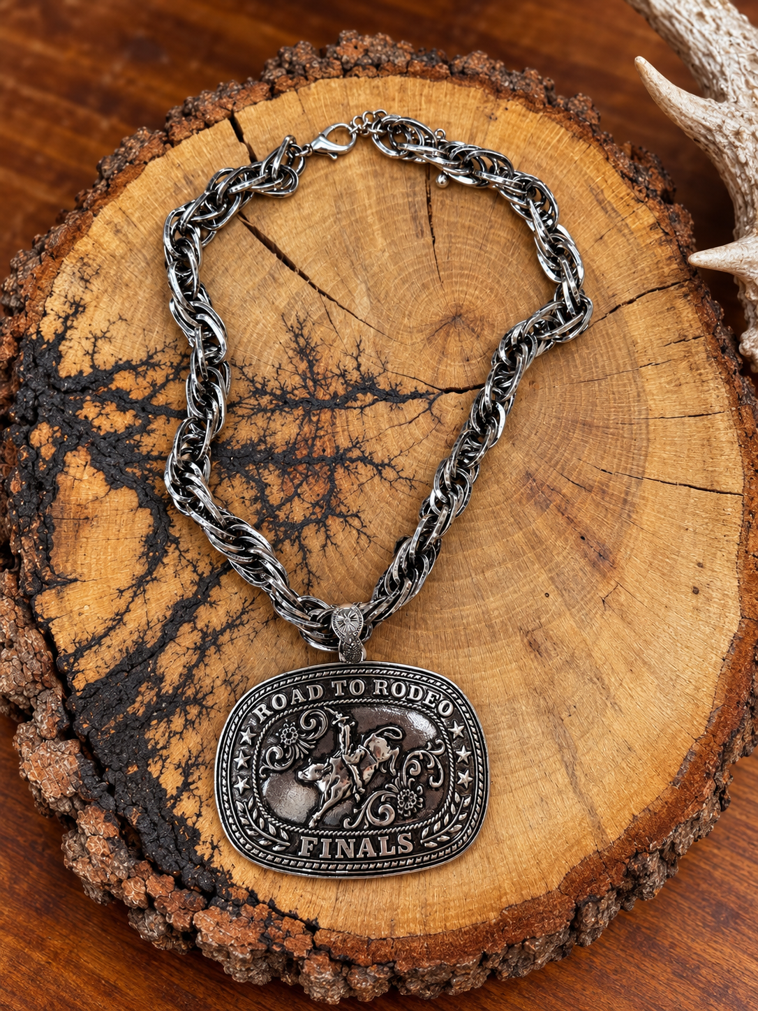 Road to Rodeo Finals silver-tone buckle pendant necklace with twisted-link chain on rustic wood