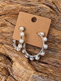 Silver-tone pearl-look hoop earrings on a kraft card and rustic wood