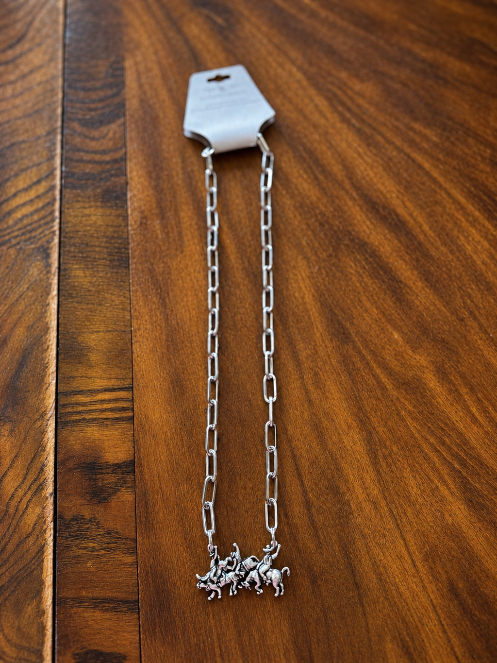 Full view of silver-tone paperclip chain necklace with running horses pendant