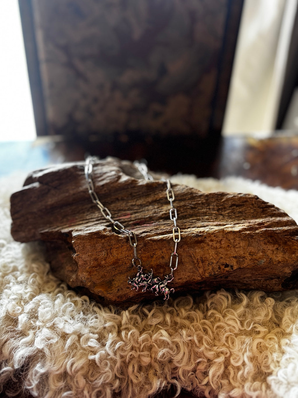 Silver-tone running horses necklace styled on rustic wood and wool