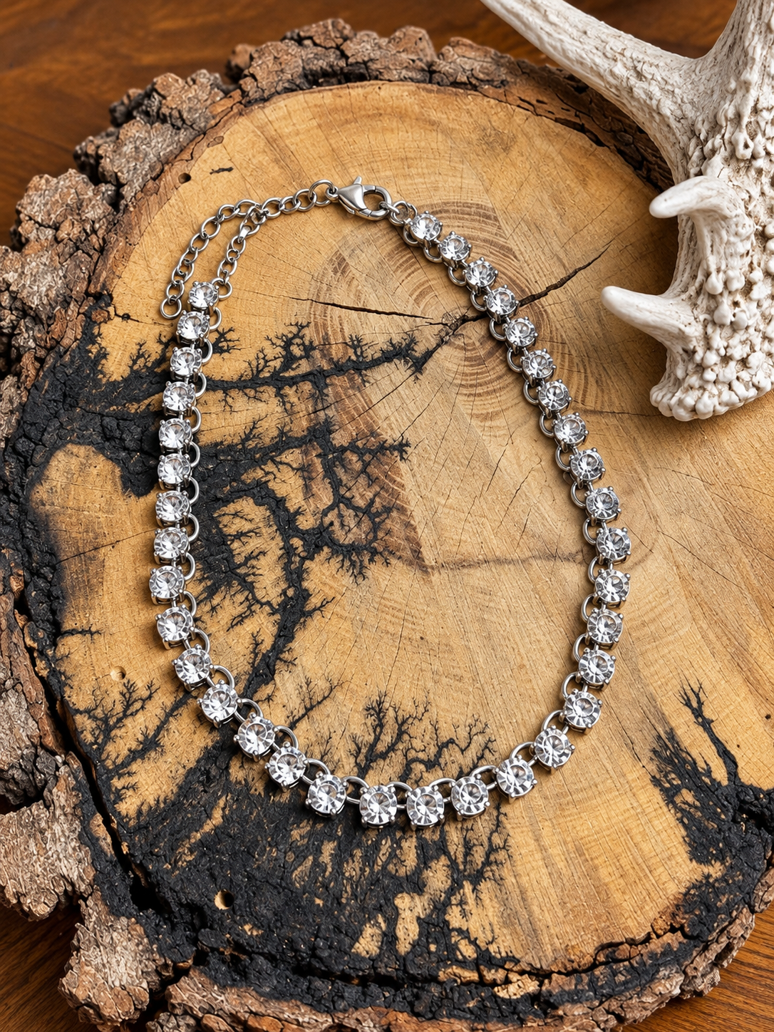 Silver-tone clear crystal link necklace with adjustable chain on rustic wood