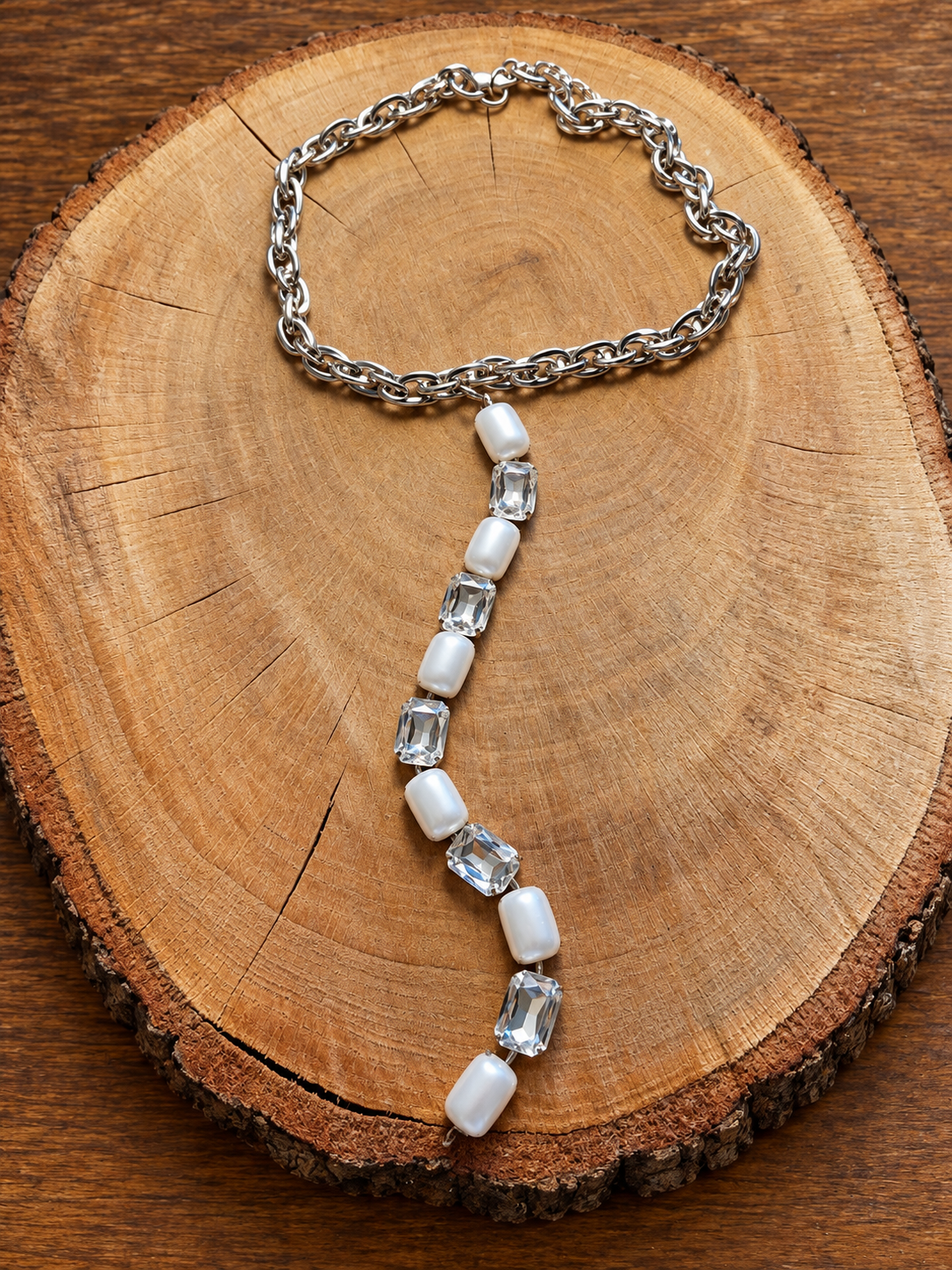 Silver-tone chain necklace with pearl-look and clear crystal long drop on wood