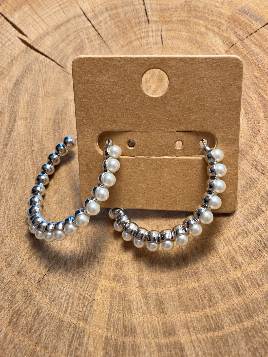 Silver-tone pearl-look hoop earrings on blank kraft card and natural wood