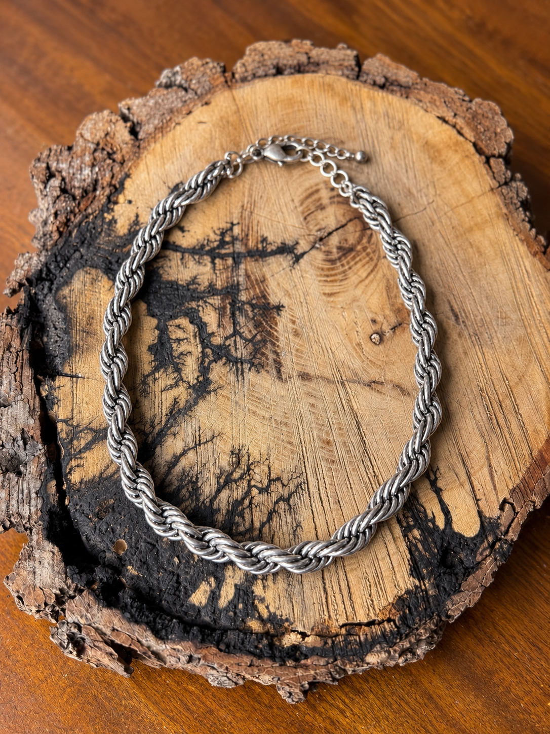 Silver-tone twisted rope chain necklace on rustic wood display