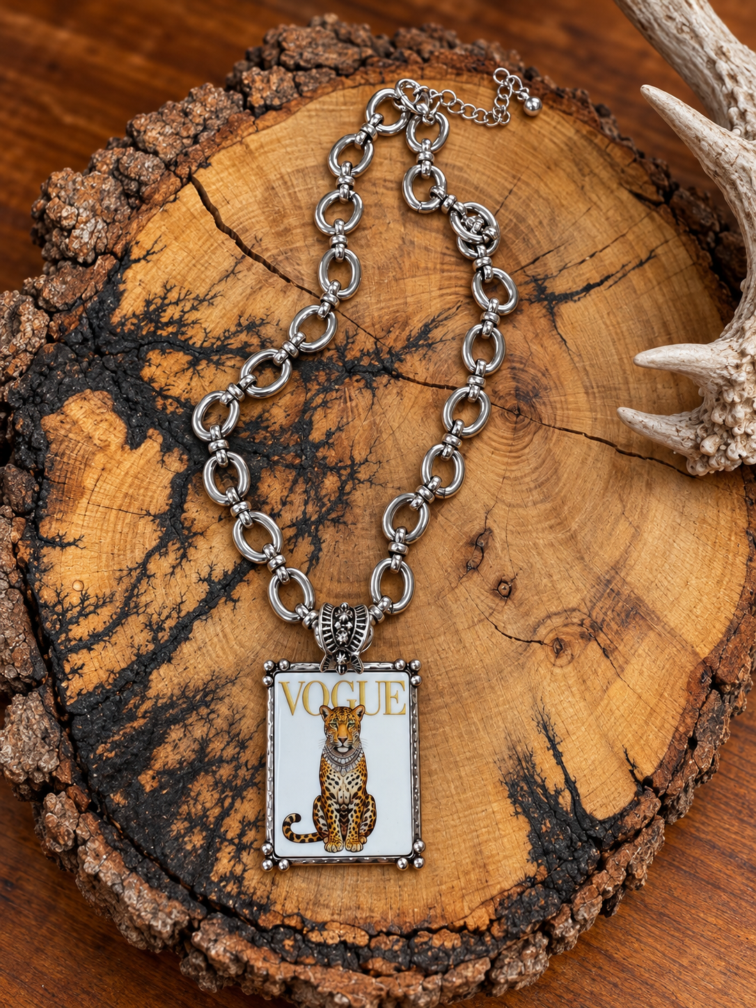 Silver-tone Vogue leopard pendant necklace with oval-link chain on rustic wood