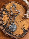 Silver-tone western scroll heart necklace displayed on a bark-edged wood slice with an antler accent
