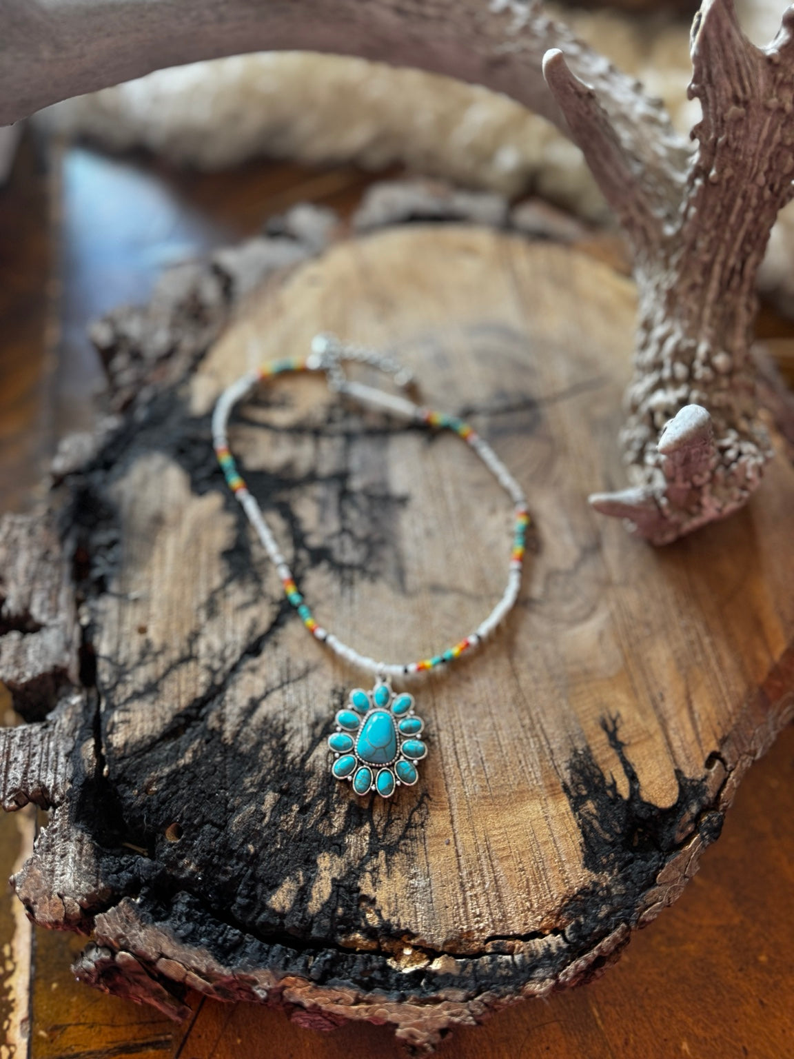 White seed bead necklace with colorful accents and turquoise-colored floral pendant