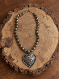 Silver-tone engraved heart beaded necklace on natural rustic wood